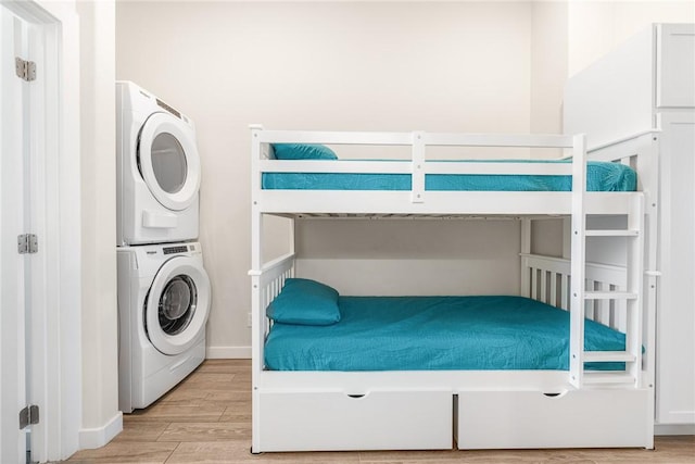 unfurnished bedroom with stacked washer / dryer and light wood-type flooring