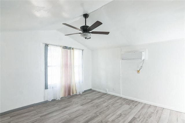 empty room with vaulted ceiling, ceiling fan, light hardwood / wood-style floors, and a wall mounted air conditioner