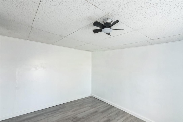 empty room with wood-type flooring, a paneled ceiling, and ceiling fan