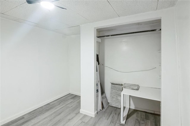 basement featuring a paneled ceiling and light wood-type flooring