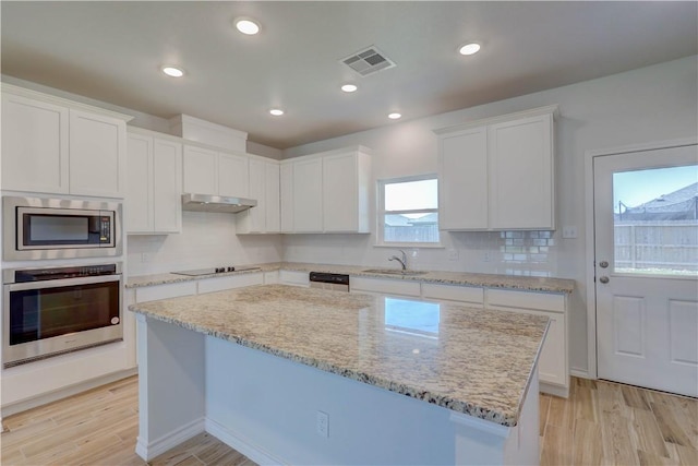 kitchen featuring sink, white cabinets, light wood-type flooring, a kitchen island, and black appliances