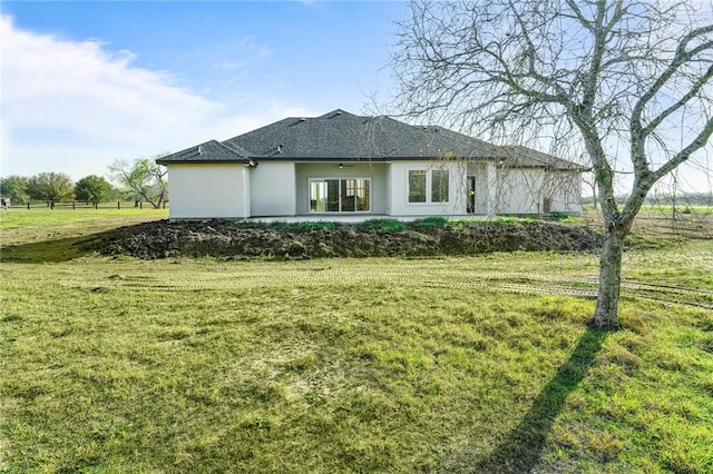 rear view of house with stucco siding and a lawn