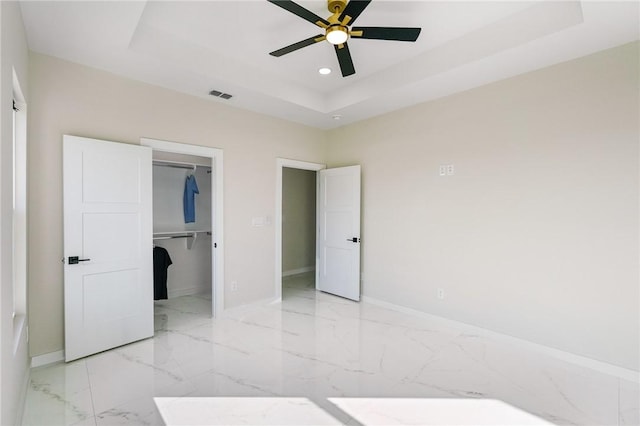 unfurnished bedroom featuring visible vents, recessed lighting, a spacious closet, a raised ceiling, and marble finish floor