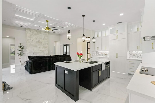 kitchen featuring light countertops, marble finish floor, coffered ceiling, and a sink