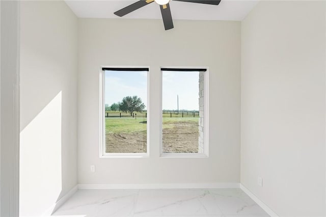 empty room with baseboards, marble finish floor, and ceiling fan