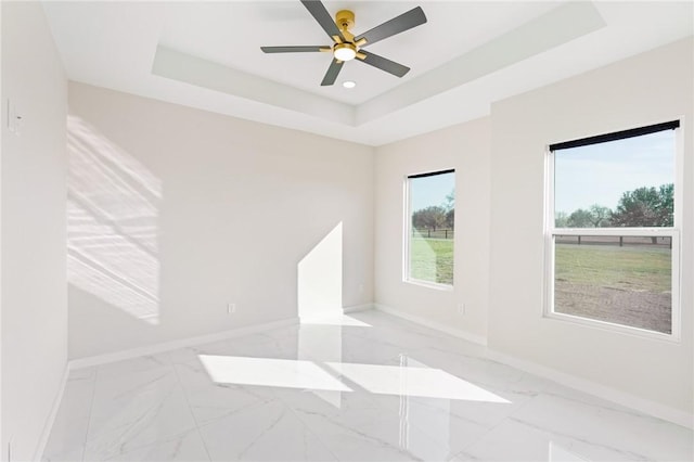 unfurnished room featuring marble finish floor, a ceiling fan, a tray ceiling, recessed lighting, and baseboards