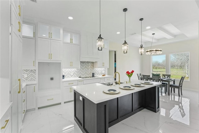 kitchen with white cabinetry, tasteful backsplash, marble finish floor, and a sink