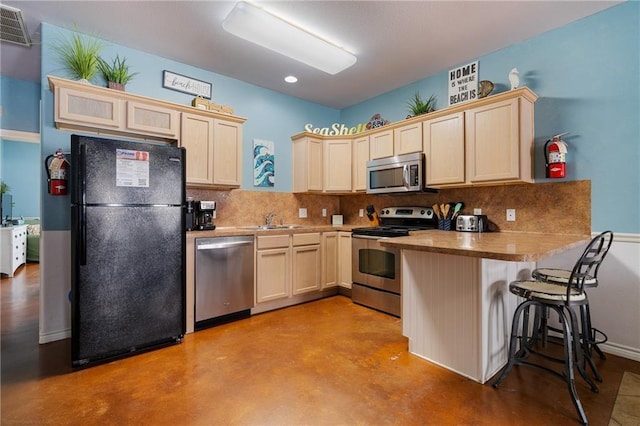 kitchen featuring sink, tasteful backsplash, a kitchen bar, kitchen peninsula, and stainless steel appliances