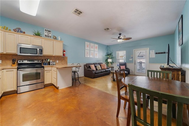 kitchen with kitchen peninsula, decorative backsplash, ceiling fan, and appliances with stainless steel finishes