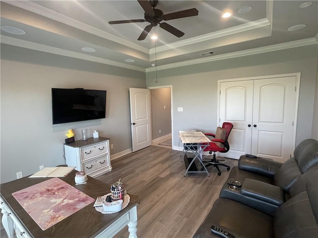 living area with visible vents, dark wood finished floors, a tray ceiling, ceiling fan, and crown molding