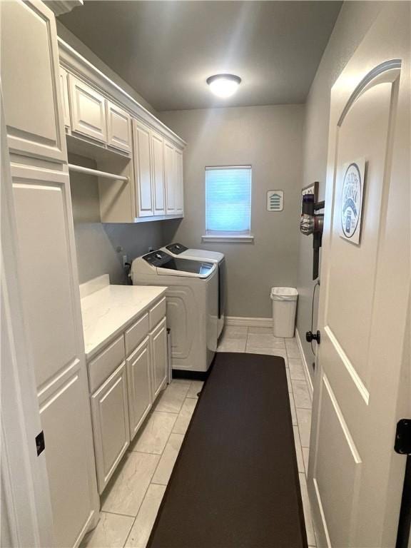 laundry room featuring light tile patterned floors, baseboards, cabinet space, and washing machine and clothes dryer