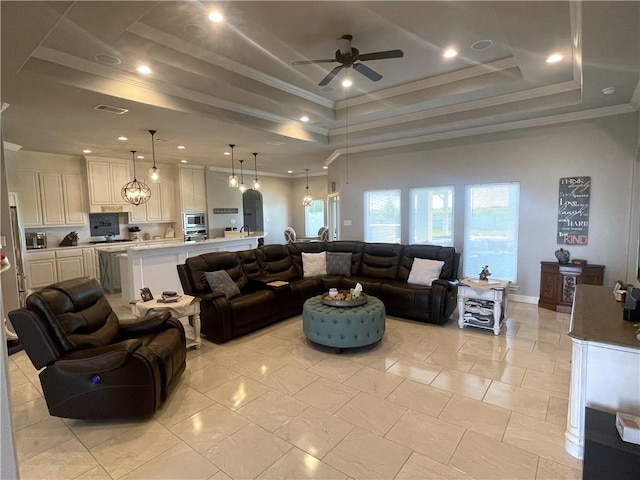 living area with visible vents, a raised ceiling, and ornamental molding