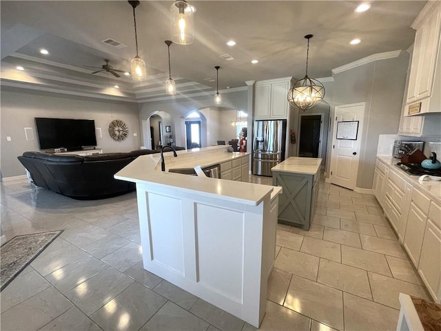 kitchen with a sink, a spacious island, arched walkways, stainless steel fridge with ice dispenser, and light countertops