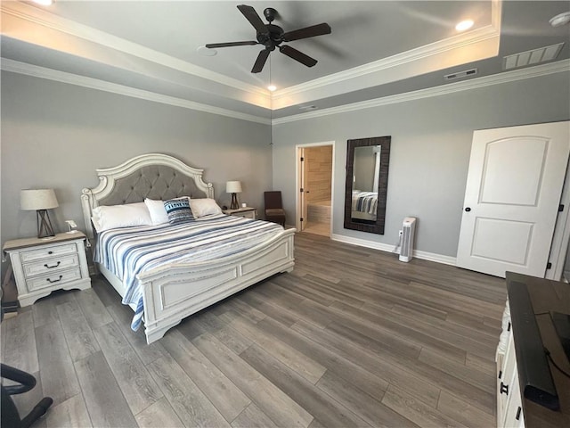 bedroom with visible vents, a raised ceiling, radiator, and wood finished floors