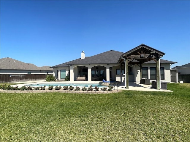 rear view of property with a patio, fence, a yard, a fenced in pool, and a chimney