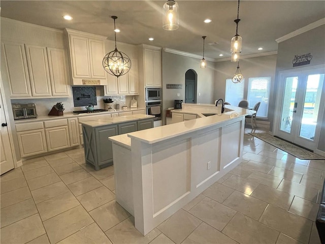 kitchen featuring stainless steel appliances, arched walkways, french doors, light countertops, and a large island with sink