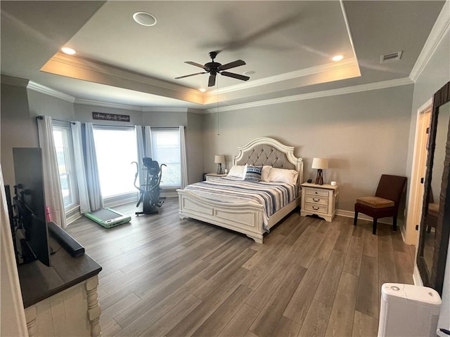 bedroom featuring visible vents, ornamental molding, a raised ceiling, and wood finished floors