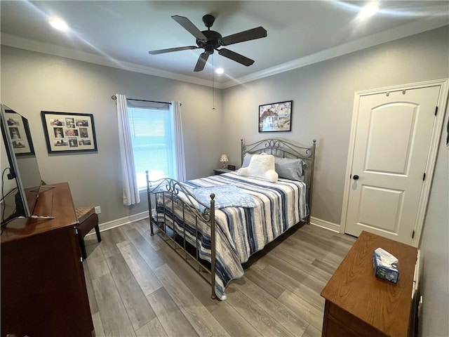 bedroom featuring baseboards, crown molding, and light wood finished floors