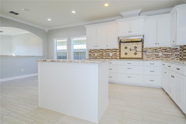 kitchen featuring white cabinetry, light stone countertops, decorative backsplash, and range hood