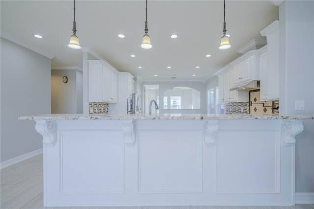 kitchen featuring pendant lighting, light stone counters, and white cabinetry