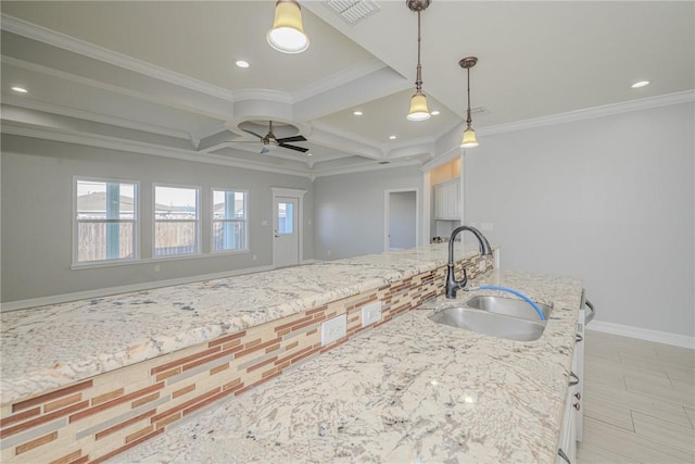 kitchen with sink, coffered ceiling, ceiling fan, crown molding, and light stone countertops