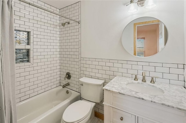 full bathroom with tiled shower / bath, vanity, toilet, and tile walls