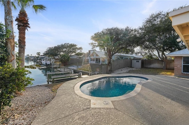 view of pool with a patio, a water view, and a boat dock