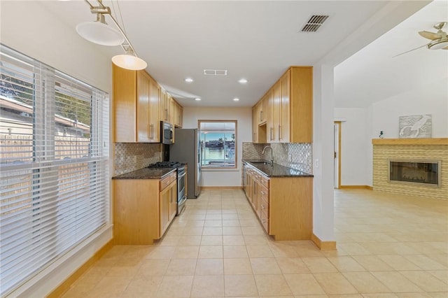 kitchen with pendant lighting, tasteful backsplash, dark stone countertops, light tile patterned floors, and stainless steel appliances