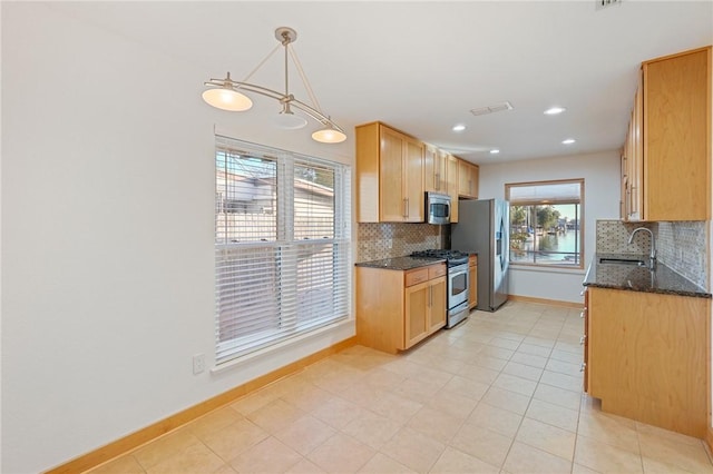 kitchen with sink, hanging light fixtures, dark stone countertops, stainless steel appliances, and decorative backsplash