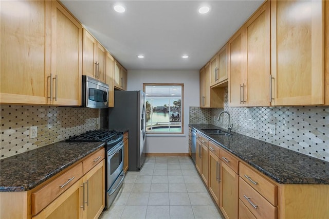 kitchen with stainless steel appliances, tasteful backsplash, sink, and dark stone counters