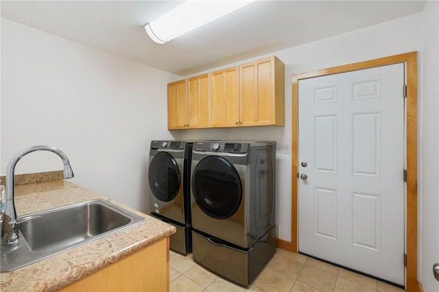 laundry area featuring sink, light tile patterned floors, washer and clothes dryer, and cabinets