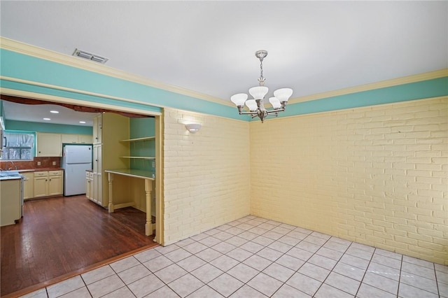5129 Goldeneye Dr, Corpus Christi, TX 78413 - empty room with brick wall, a chandelier, crown molding, and light tile patterned floors