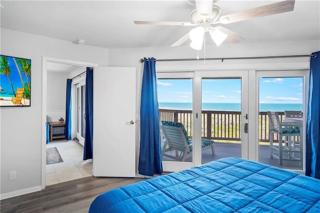 bedroom with a water view, ceiling fan, access to exterior, wood-type flooring, and french doors