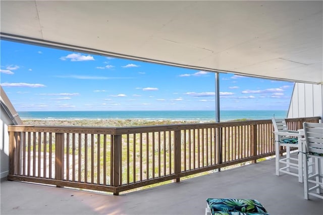 unfurnished sunroom featuring a view of the beach and a water view