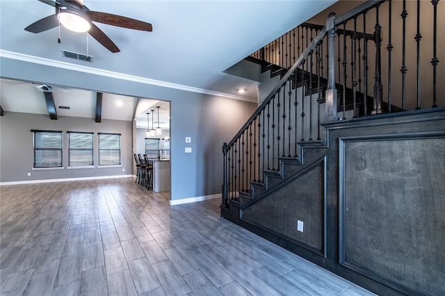 stairs featuring hardwood / wood-style floors, ceiling fan, lofted ceiling with beams, and ornamental molding