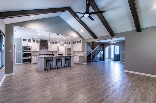 living room featuring high vaulted ceiling, light wood-type flooring, ceiling fan, and beamed ceiling