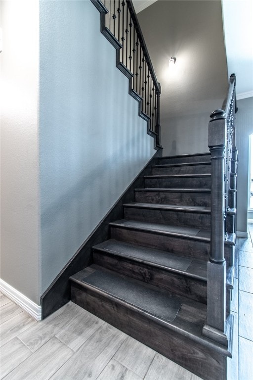 stairway with hardwood / wood-style flooring and crown molding