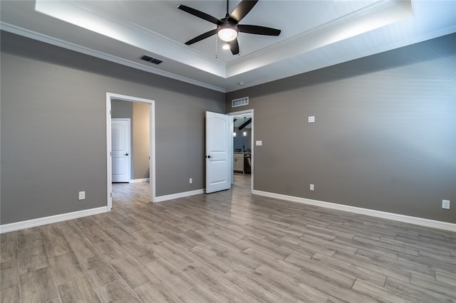 unfurnished bedroom with ornamental molding, light wood-type flooring, ceiling fan, and a tray ceiling