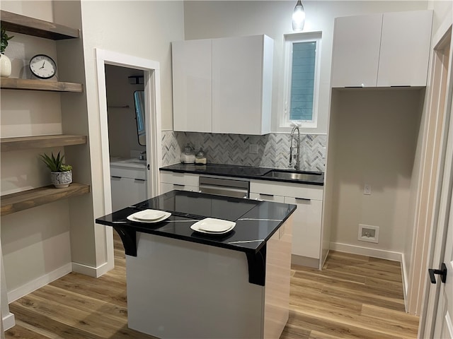 kitchen featuring tasteful backsplash, white cabinetry, sink, light hardwood / wood-style floors, and a center island