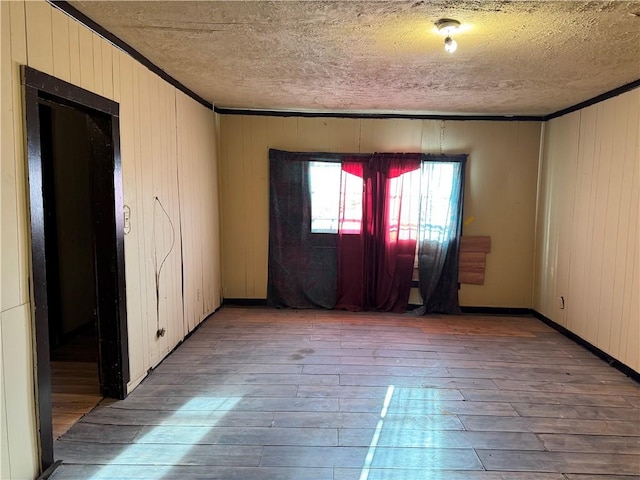 4721 Molina Dr, Corpus Christi, TX 78416 - empty room featuring wood-type flooring, a textured ceiling, ornamental molding, and wood walls