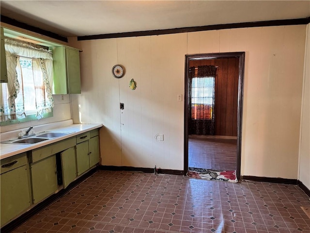 4721 Molina Dr, Corpus Christi, TX 78416 - kitchen with green cabinets, baseboards, a sink, light countertops, and wood walls