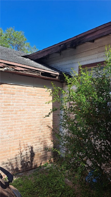 view of side of property with brick siding and roof with shingles