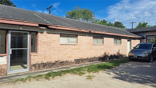 view of property exterior featuring brick siding and a shingled roof