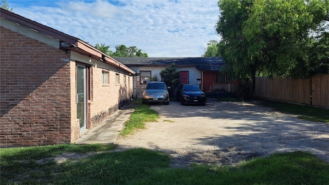 view of side of property with driveway, fence, and brick siding