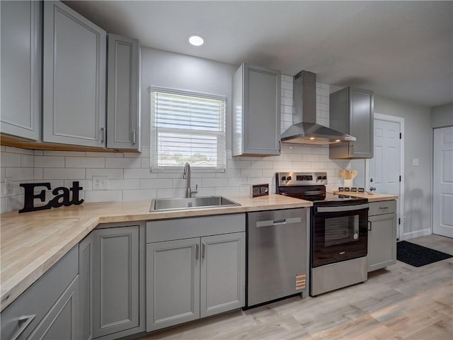 222 N 9th St, Aransas Pass, TX 78336 - kitchen featuring stainless steel appliances, wall chimney range hood, a sink, gray cabinets, and recessed lighting