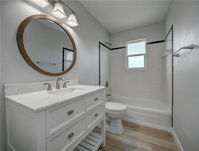222 N 9th St, Aransas Pass, TX 78336 - full bathroom with wood finished floors, toilet, vanity, tub / shower combination, and a textured wall