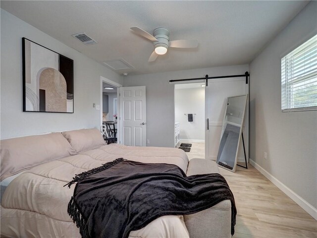 222 N 9th St, Aransas Pass, TX 78336 - bedroom with light wood-type flooring, a barn door, ceiling fan, and baseboards