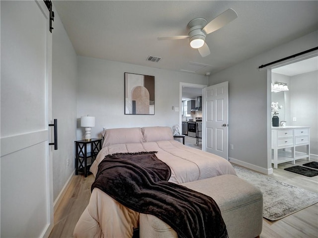 222 N 9th St, Aransas Pass, TX 78336 - bedroom with a barn door, light wood-style flooring, baseboards, and ceiling fan