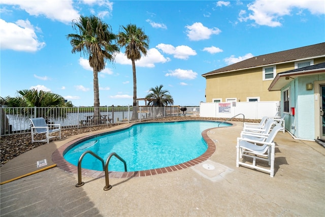 view of swimming pool with a patio area and a water view