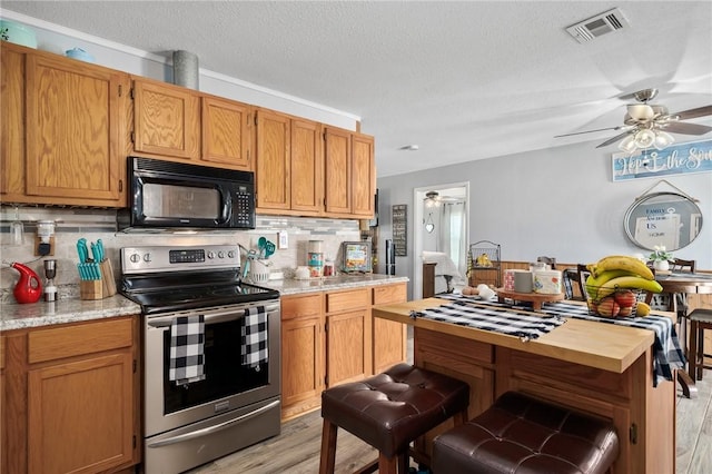 kitchen featuring a textured ceiling, backsplash, light hardwood / wood-style floors, and stainless steel range with electric cooktop